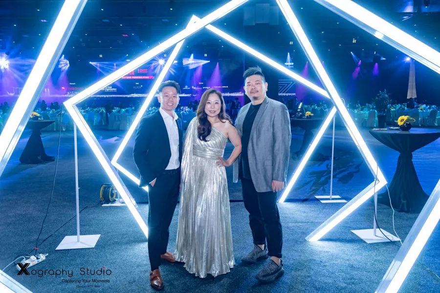 Guests posing in a glowing hexagon light arch